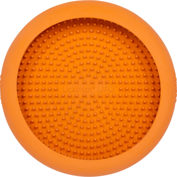 LickiMat UFO in orange stuck to a wall