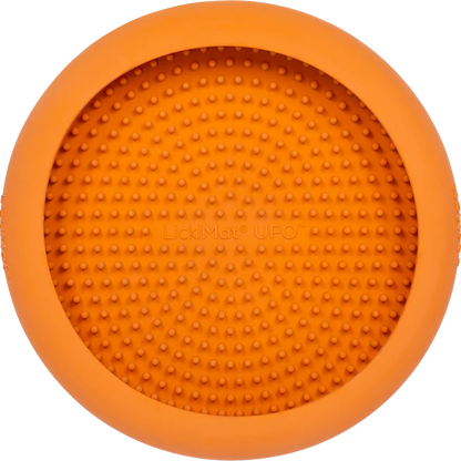 LickiMat UFO in orange stuck to a wall