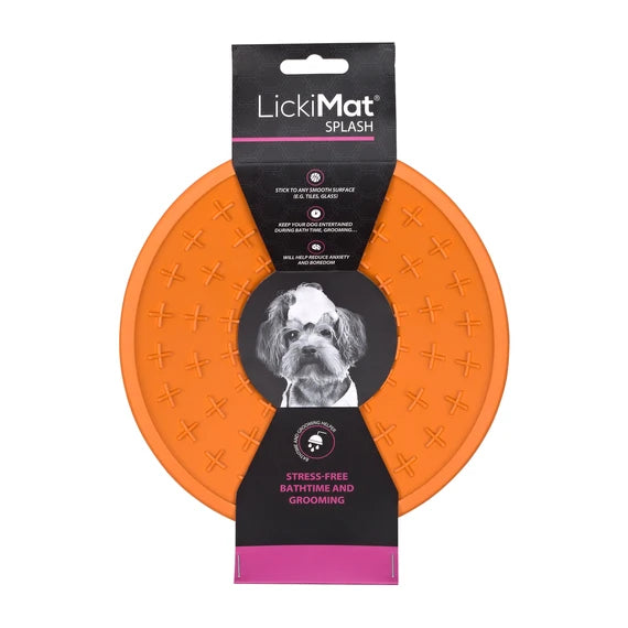 LickiMat Splash in orange stuck to a wall